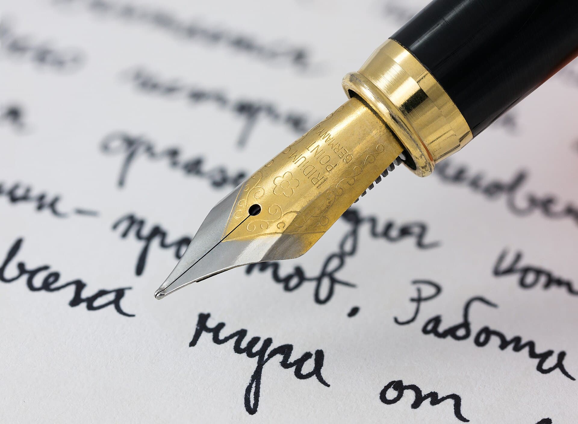 A fountain pen writing a line of ink on cream paper
