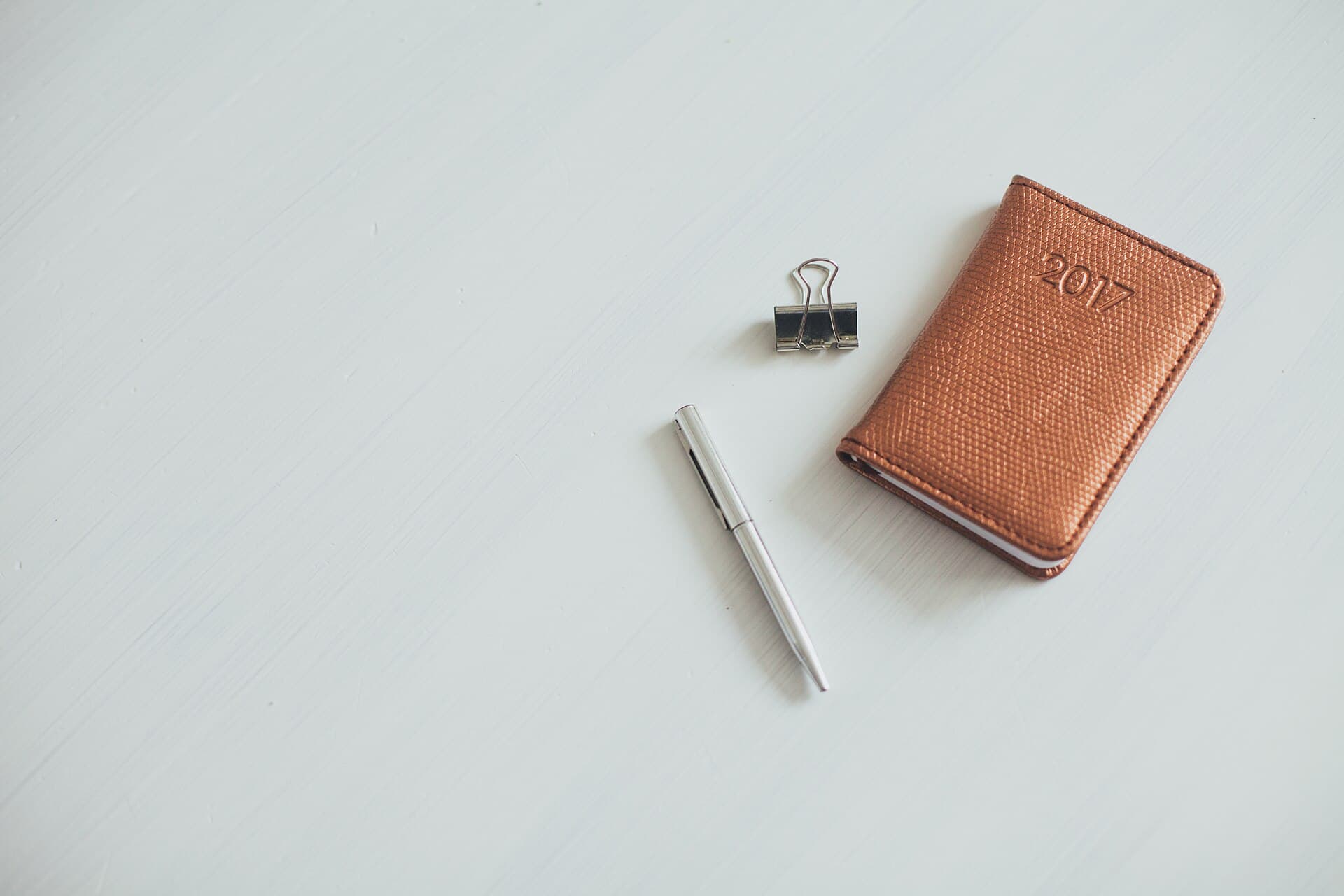 An open leather notebook with a pen resting on the page