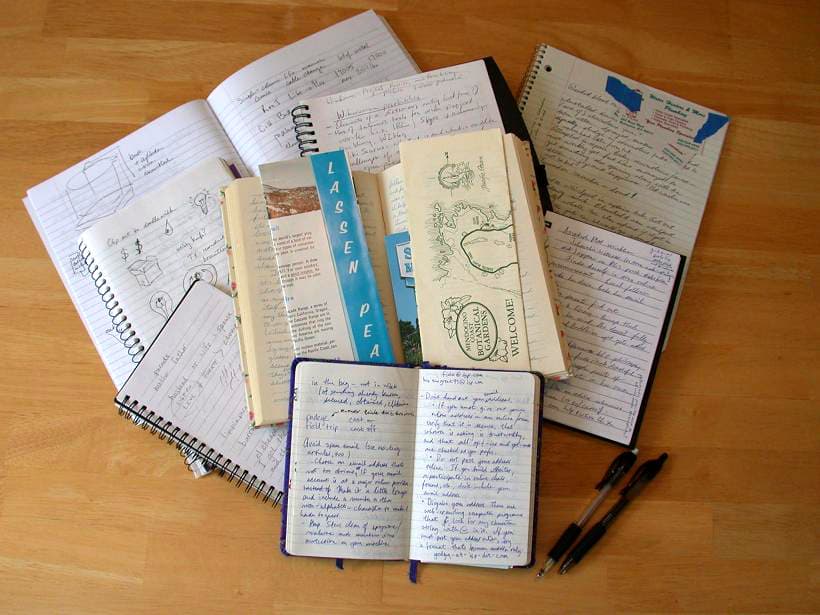 A stack of cloth-bound notebooks and journals